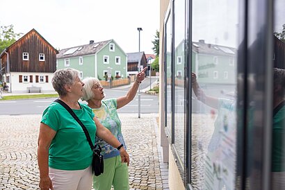 Menschen stehen vor der Infotafel in Feilitzsch.